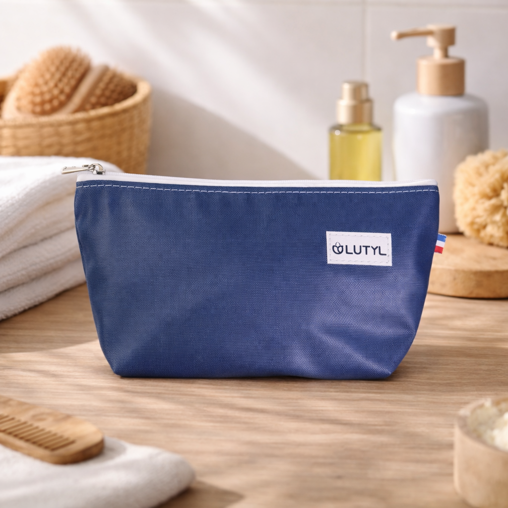 Trousse compacte bleu marine Lutyl en toile enduite posée sur un meuble de salle de bain avec accessoires de toilette