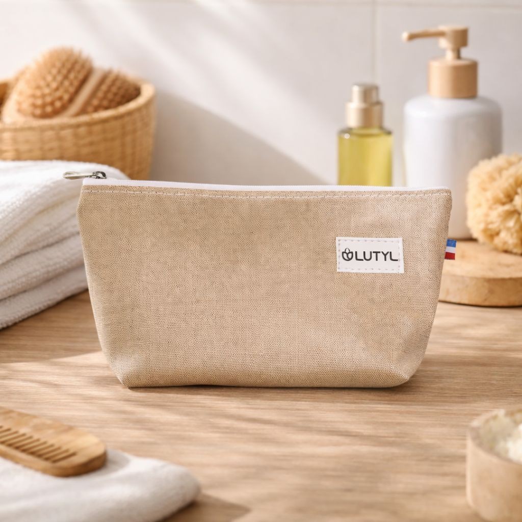 Trousse compacte couleur lin Lutyl en toile enduite posée sur un meuble de salle de bain avec accessoires de toilette