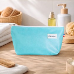 Trousse compacte bleu turquoise Lutyl en toile enduite posée sur un meuble de salle de bain avec accessoires de toilette