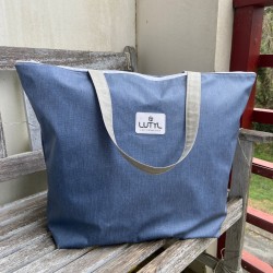 Sac zippé XL Lutyl bleu denim en toile enduite posé sur banc extérieur