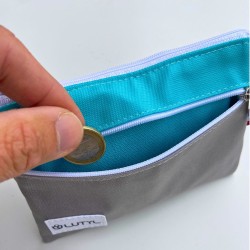 Main rangeant une pièce dans le porte-monnaie double zip Lutyl